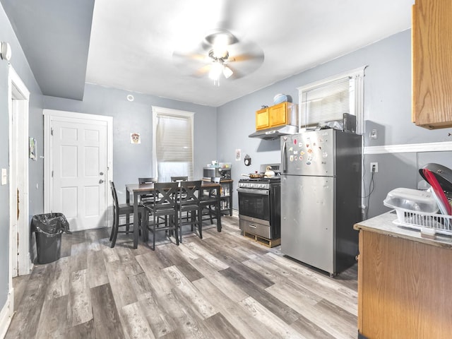 kitchen with under cabinet range hood, stainless steel appliances, a ceiling fan, light countertops, and light wood-type flooring