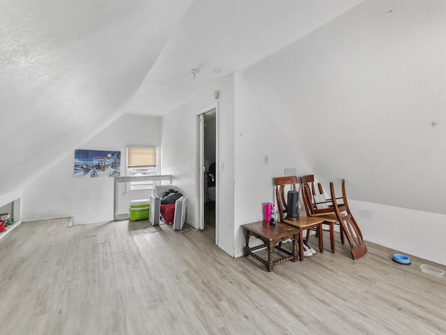 bonus room with light wood-style floors, lofted ceiling, and baseboards