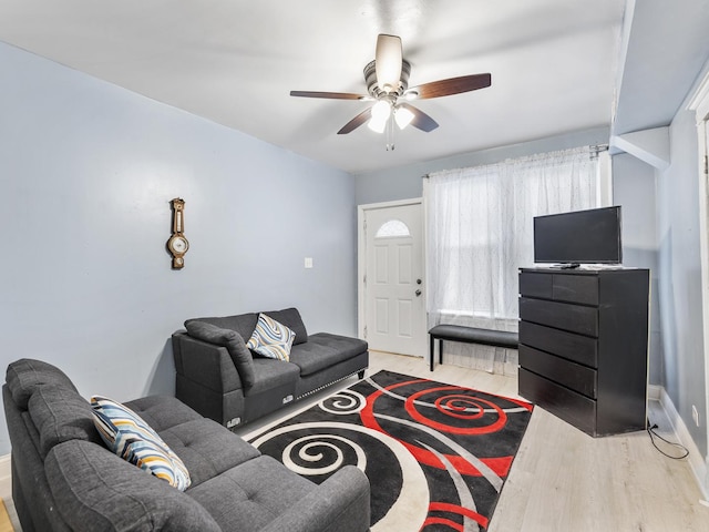 living area featuring light wood-style flooring, baseboards, and ceiling fan