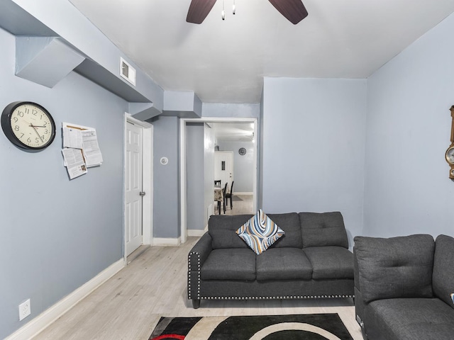 living area featuring a ceiling fan, baseboards, visible vents, and light wood finished floors