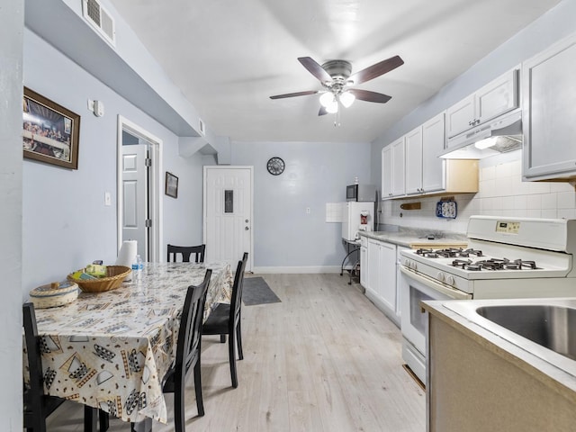 kitchen with white range with gas stovetop, visible vents, light countertops, under cabinet range hood, and white cabinetry