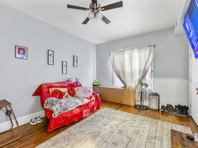 bedroom with a ceiling fan, baseboards, and wood finished floors