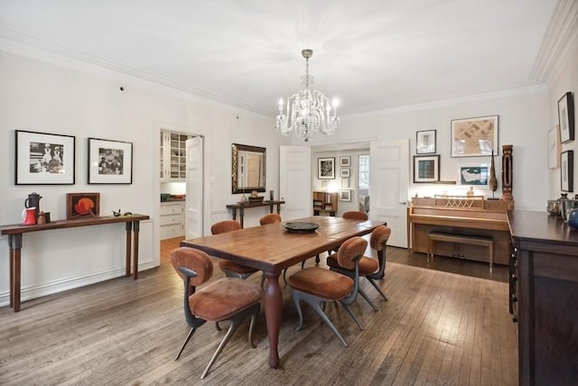 dining area featuring dark wood-type flooring, a chandelier, and crown molding