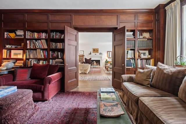 living area with built in shelves, light wood-type flooring, and a fireplace