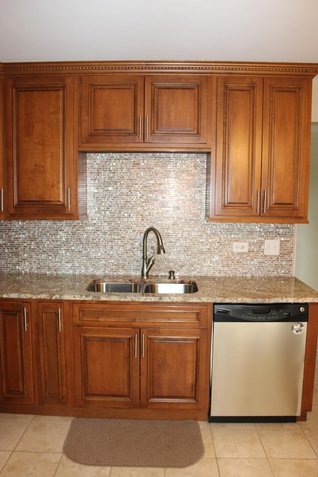 kitchen with stainless steel dishwasher, a sink, light stone counters, and brown cabinets