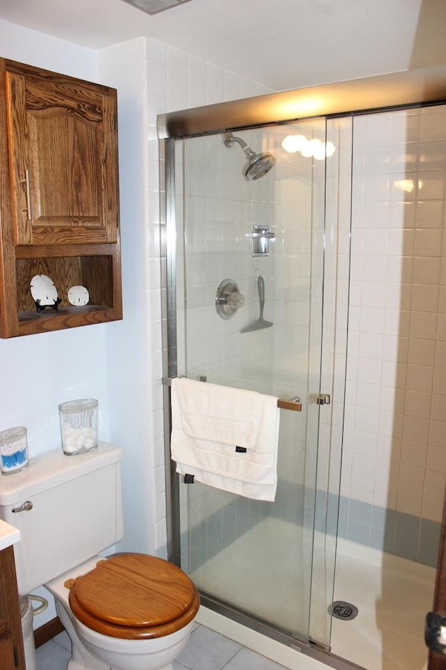 bathroom featuring a stall shower, tile patterned flooring, and toilet