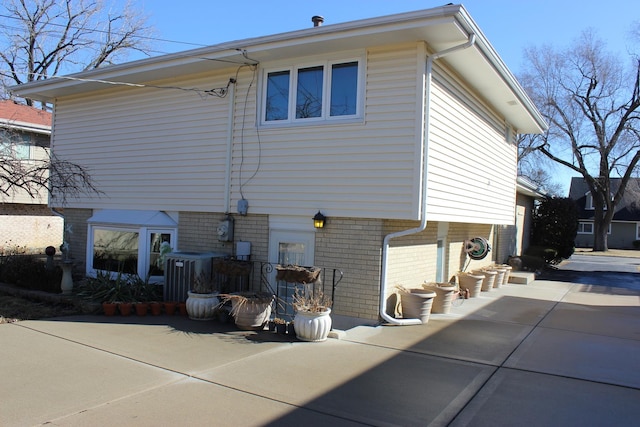 rear view of house featuring central AC, brick siding, and a patio