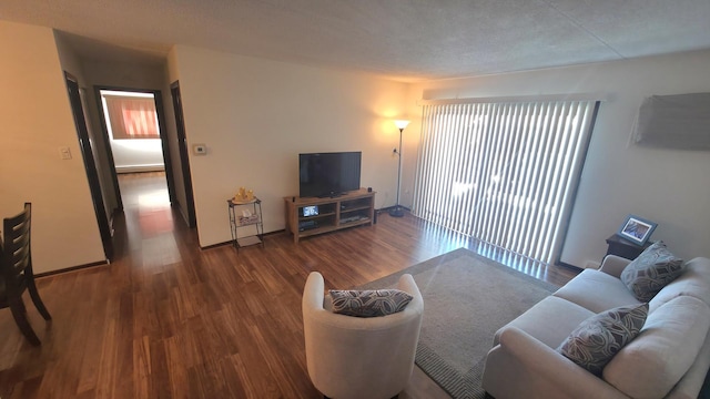 living area featuring a textured ceiling, baseboards, and wood finished floors