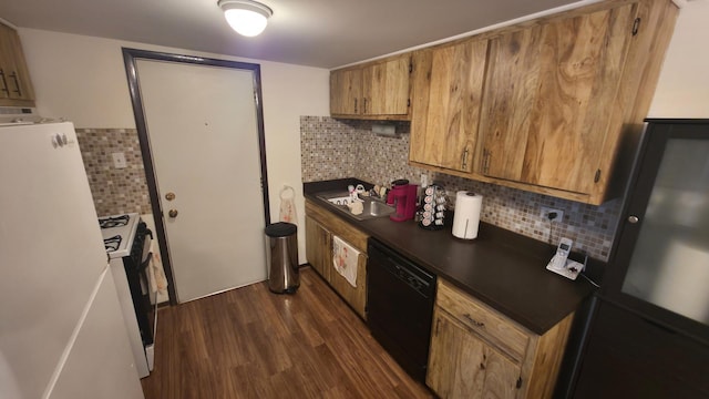 kitchen featuring dark wood finished floors, brown cabinetry, dark countertops, black appliances, and a sink