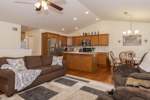 living area featuring light wood-type flooring, recessed lighting, ceiling fan with notable chandelier, and lofted ceiling