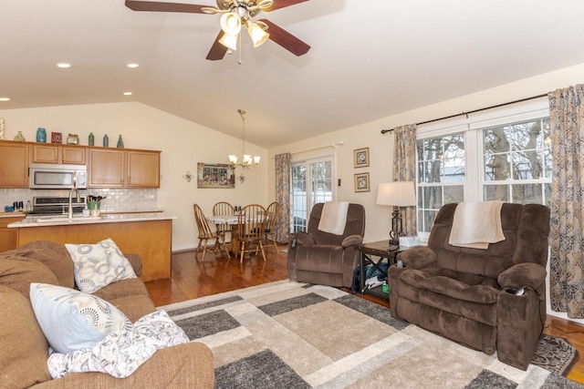 living area featuring lofted ceiling, dark wood-style flooring, ceiling fan with notable chandelier, and recessed lighting