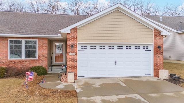 single story home with an attached garage, a shingled roof, concrete driveway, and brick siding