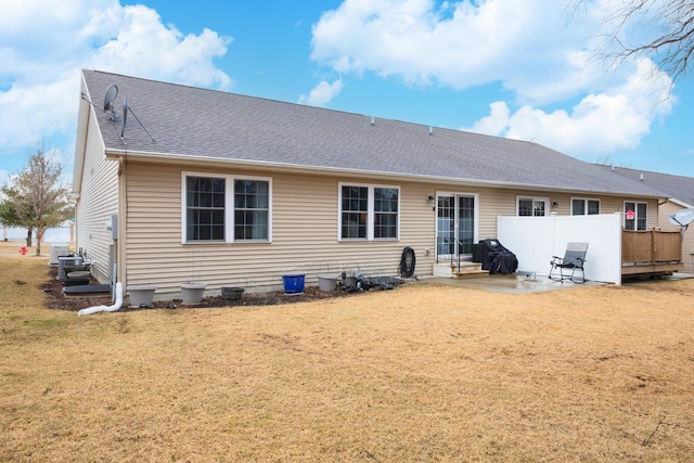 back of house with a yard, a shingled roof, and a patio