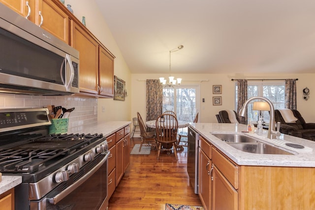 kitchen with lofted ceiling, stainless steel appliances, a sink, an island with sink, and pendant lighting