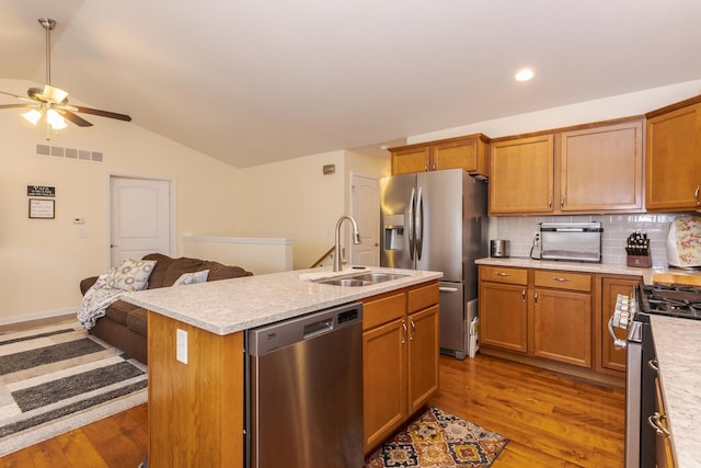 kitchen featuring a sink, visible vents, light countertops, appliances with stainless steel finishes, and a center island with sink