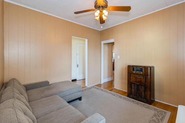 living area with ornamental molding, a ceiling fan, and wood finished floors