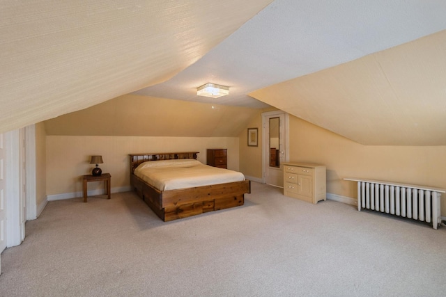 bedroom with radiator, light carpet, baseboards, and vaulted ceiling