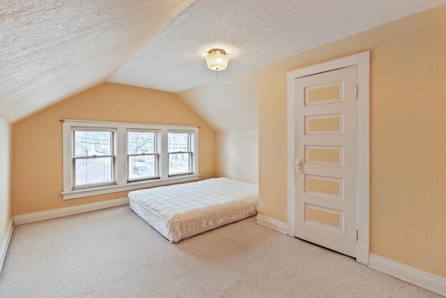 bedroom featuring lofted ceiling, carpet, and a textured ceiling