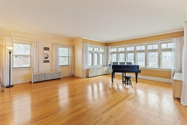 sitting room featuring baseboards, light wood-type flooring, radiator, radiator heating unit, and crown molding