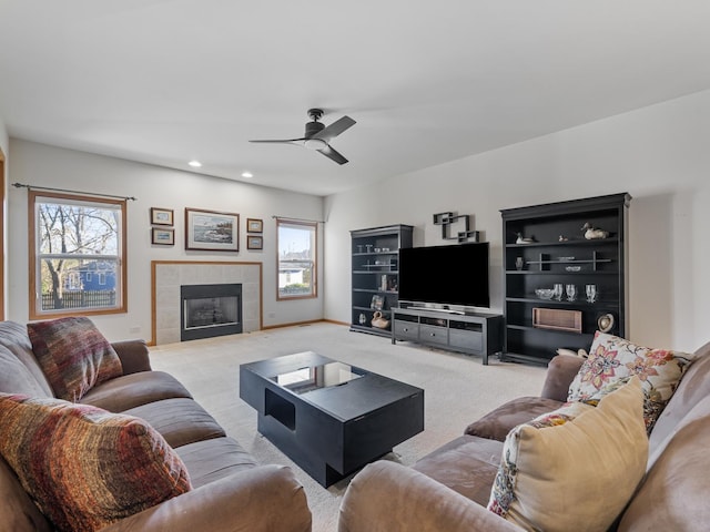 living room with light carpet, a tile fireplace, a ceiling fan, and a healthy amount of sunlight