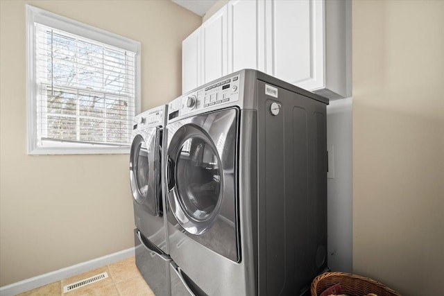 washroom with light tile patterned floors, cabinet space, visible vents, washing machine and dryer, and baseboards