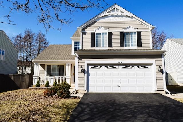 traditional home with a porch, driveway, an attached garage, and fence