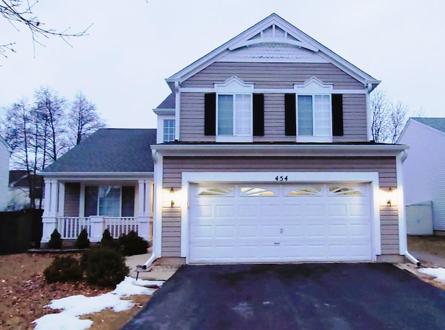 view of front facade with aphalt driveway, an attached garage, and covered porch