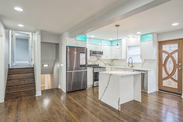 kitchen with dark wood-style floors, a center island, decorative light fixtures, appliances with stainless steel finishes, and white cabinetry