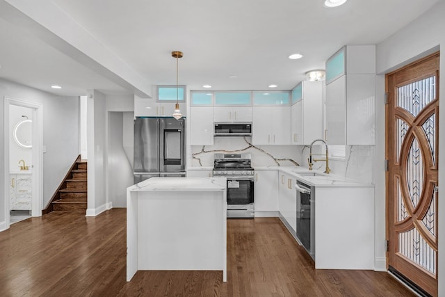 kitchen with a kitchen island, a sink, white cabinetry, hanging light fixtures, and appliances with stainless steel finishes