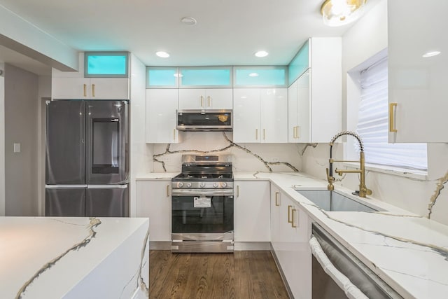 kitchen featuring dark wood finished floors, appliances with stainless steel finishes, white cabinetry, a sink, and modern cabinets