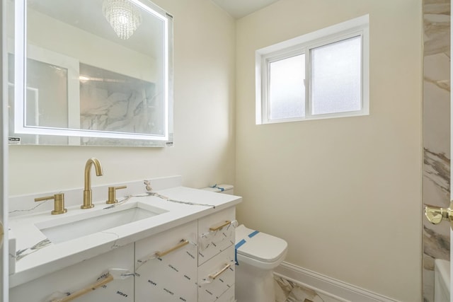 full bath featuring toilet, vanity, and baseboards