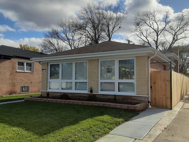 bungalow-style home featuring brick siding, a front lawn, and roof with shingles