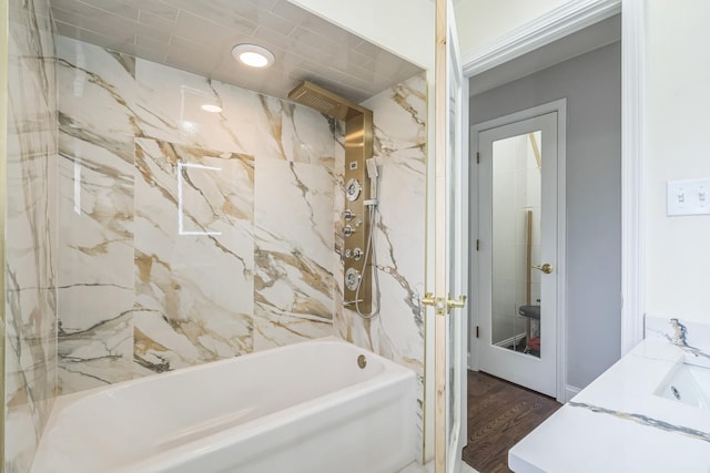 full bath featuring vanity, wood finished floors, and a combined bath / shower with marble appearance