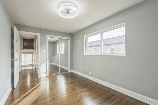 unfurnished bedroom featuring a closet, dark wood-style flooring, visible vents, and baseboards