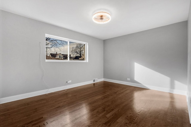 spare room with visible vents, baseboards, and wood finished floors