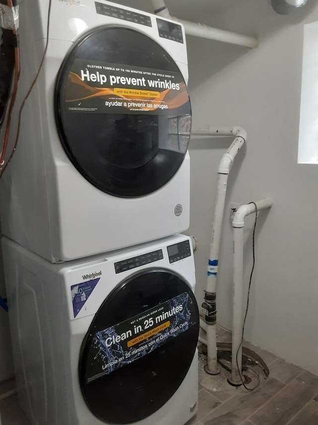 clothes washing area featuring stacked washer / drying machine, laundry area, and light wood-style flooring