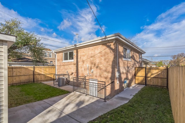 rear view of property with a gate, a patio area, brick siding, and a fenced backyard