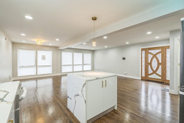 kitchen featuring white cabinets, dark wood-style floors, light stone counters, and pendant lighting