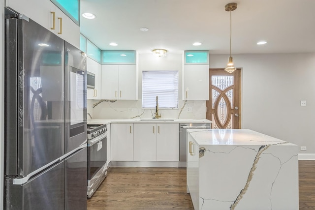 kitchen featuring stainless steel appliances, a sink, white cabinetry, modern cabinets, and decorative light fixtures