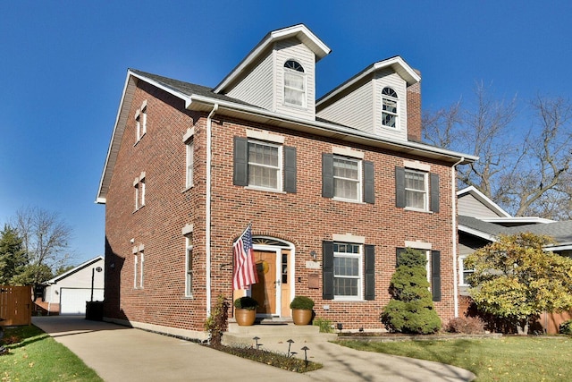 view of front of home with an outbuilding, brick siding, and a detached garage