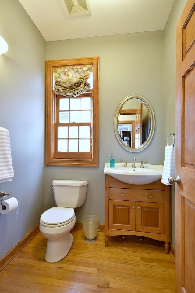 bathroom with toilet, wood finished floors, visible vents, and baseboards