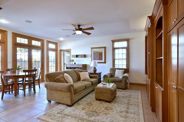 living room with a ceiling fan, baseboards, and light tile patterned floors