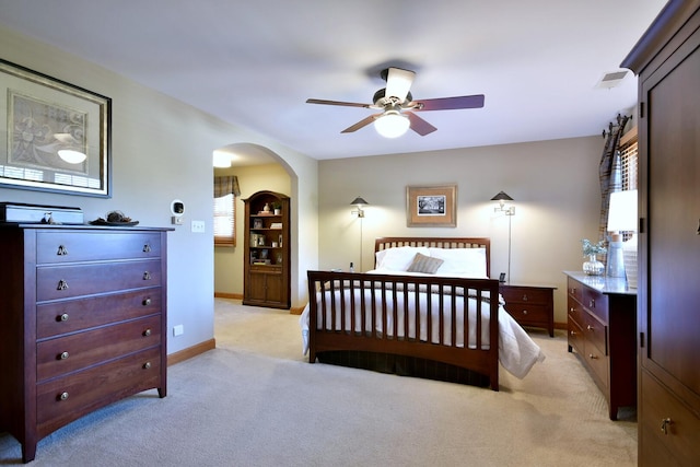 bedroom with arched walkways, baseboards, visible vents, and light colored carpet