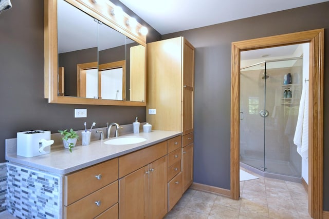 bathroom featuring a stall shower, vanity, baseboards, and tile patterned floors