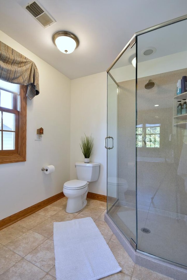 bathroom featuring toilet, a stall shower, visible vents, and baseboards