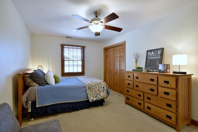 bedroom with light carpet, ceiling fan, visible vents, and a closet