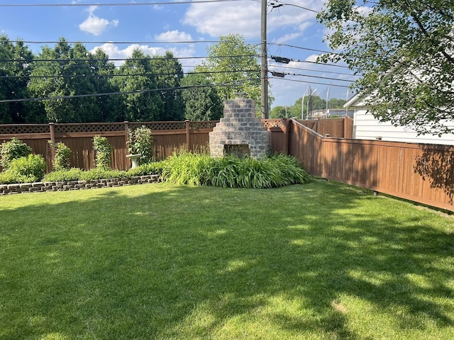 view of yard with an outdoor brick fireplace and fence