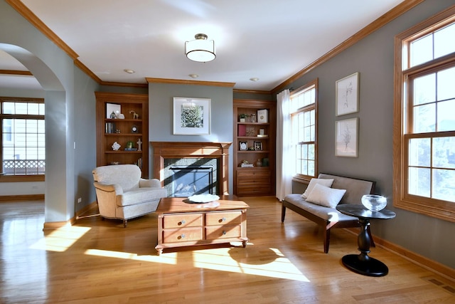 living area with baseboards, arched walkways, visible vents, wood finished floors, and a fireplace