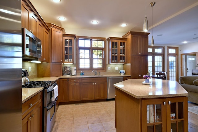 kitchen with stainless steel appliances, hanging light fixtures, backsplash, and brown cabinets