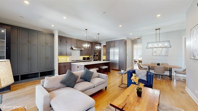 living room featuring a chandelier, recessed lighting, light wood-style flooring, and baseboards